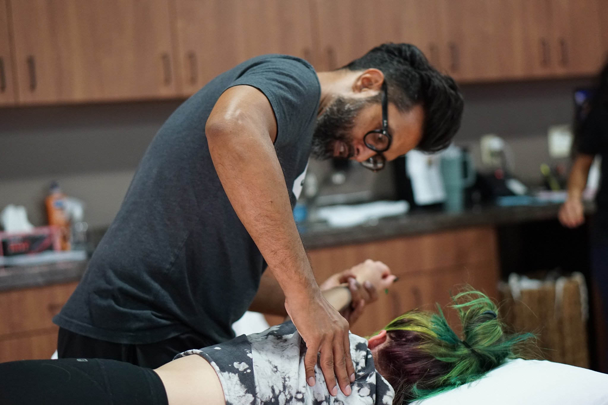 Synergy Physical Therapy owner, Vincent Peries, DPT, performs manual therapy on a female patient's upper back. 